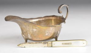 Edward VII hallmarked silver sauce boat with shaped edge and scroll handle, raised on three feet,