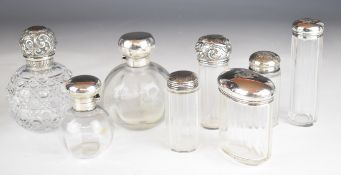 Eight Victorian and later hallmarked silver topped dressing table scent bottles including a