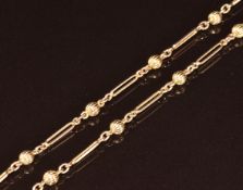 A c1920 9ct gold guard chain made up of ridged spherical beads and elongated links, 14g, 84cm