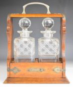19th or early 20thC oak tantalus with metal fretwork mounts and two cut glass decanters, H33cm