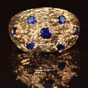 A 9ct gold ring set with seven sapphires with a textured finish, 2.6g, size K