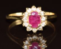 A 14k gold ring set with an oval cut ruby surrounded by diamonds, 2.6g, size K