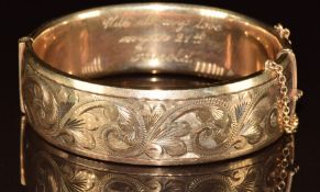 A 9ct gold bangle with engraved scrolling decoration, 49.9g, 5.8 x 5.2cm