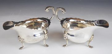 Pair of George V hallmarked silver sauce boats with shaped edges and scroll handles, raised on three
