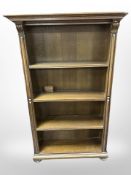 An oak open bookcase on bun feet,
