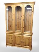 A contemporary pine glazed triple door display cabinet,