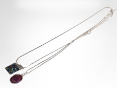 Two silver-mounted mother of pearl pendants on chains.