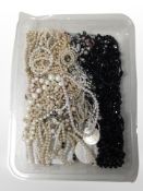 A shallow tray containing faux pearl necklaces, mourning jewellery, etc.