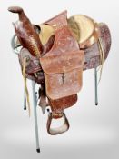 A tooled leather saddle on metal stand.