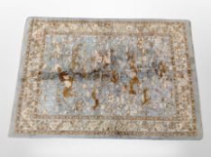 A machine made rug of Persian design depicting figures hunting on horseback,