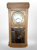 An early 20th century oak 8-day wall clock with silvered dial.