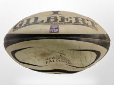 A Newcastle Falcons rugby ball with team signatures.