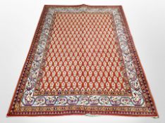 A machine-made rug of Persian design on red ground, 200cm x 136cm.