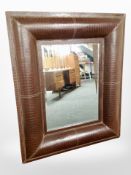 A contemporary over mantel mirror in crocodile effect frame,
