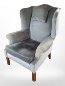 An early 20th-century wingback armchair in blue upholstery.