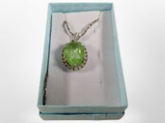 A silver pendant on chain with faceted lime green stone.