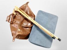 A vintage luggage case, a stitched brown leather hold all, and a bundle of four walking sticks.