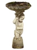 A weathered concrete pedestal bird bath with cherub support,