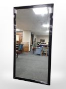 A contemporary bevelled mirror in high gloss ebonised frame,