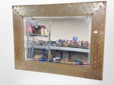 A contemporary metal studded mirror in the Arts and Crafts style,