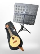 A contemporary four string ukulele in carry case and a Tiger folding music stand with carry bag.