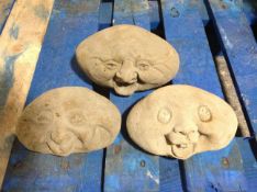 Three concrete happy face ornaments, largest 21cm wide.