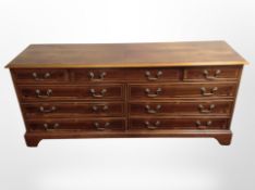A reproduction yew wood low sideboard, fitted nine drawers,