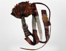 Two African knives in decorative leather sheaths.
