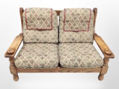 An oak-framed two-seater settee, 140cm wide x 86cm deep x 90cm high.