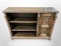 An early 20th century heavily carved oak open bookcase on bun feet,