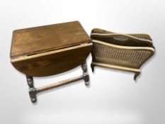 An oak drop leaf table and bergere magazine rack