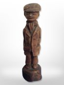 A hand carved figure of a man wearing a flat cap,
