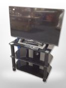 A Sony Bravia 32 inch LCD TV with lead and remote on glass TV stand