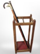 An Edwardian oak stick stand containing three walking sticks,