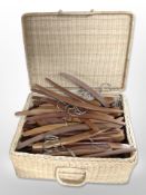 A wicker hamper containing a quantity of 1970s Scandinavian teak coat hangers.