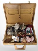 A vintage tan leather briefcase containing an Indonesian silhouette puppet, other puppets, etc.