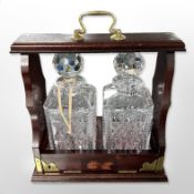 A reproduction mahogany Tantalus with two crystal decanters and key, height 34cm including handle.