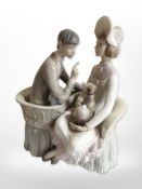 A Lladró figure of a lady and gentleman sat on a conversation settee.