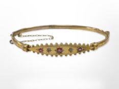 An antique 9ct yellow gold bangle set with three rubies and two small diamonds,