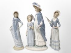 A Lladró figure of a lady holding a cane, a Nao figure and a Nao figure group, tallest 37cm.