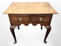 A George III oak lowboy fitted two drawers and raised on pad feet,