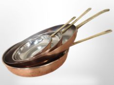 Four copper-finish cooking pans with brass handles, largest 47cm long.