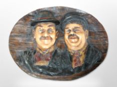 A composition oval plaque depicting Stan Laurel and Oliver Hardy,