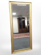 A large contemporary gilt bevelled floor-standing mirror, 165cm x 75cm.