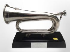 A chrome-plated bugle on plinth with plaque inscribed 'presented to Colonel M P Colacicchi by the