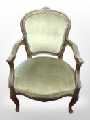 A continental carved salon armchair in green dralon upholstery.