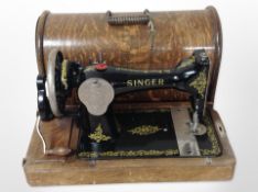 An antique Singer hand sewing machine in oak case.