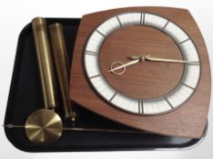 A Kieningen teak wall clock with pendulum and two weights.