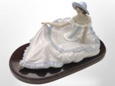 A Nao figure of a seated lady wearing a dress, No. 1265, on wooden plinth, overall 38cm wide.