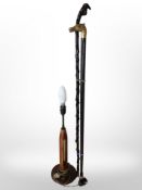 A lamp base and two walking sticks, one with horse head pommel.